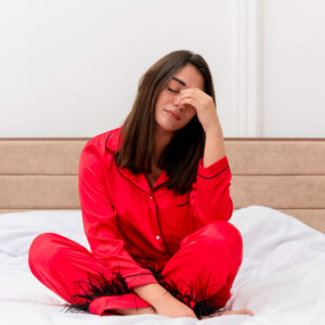 A tired women sitting on bed.