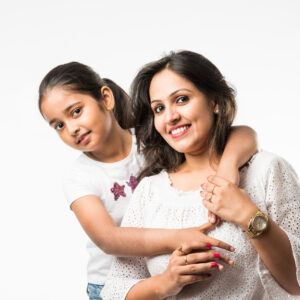 Indian mother and daughter smiling, hugging, and playing together on a white background.