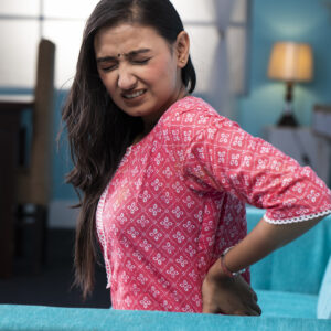 Mature woman holding back in pain, showing discomfort and strain.
